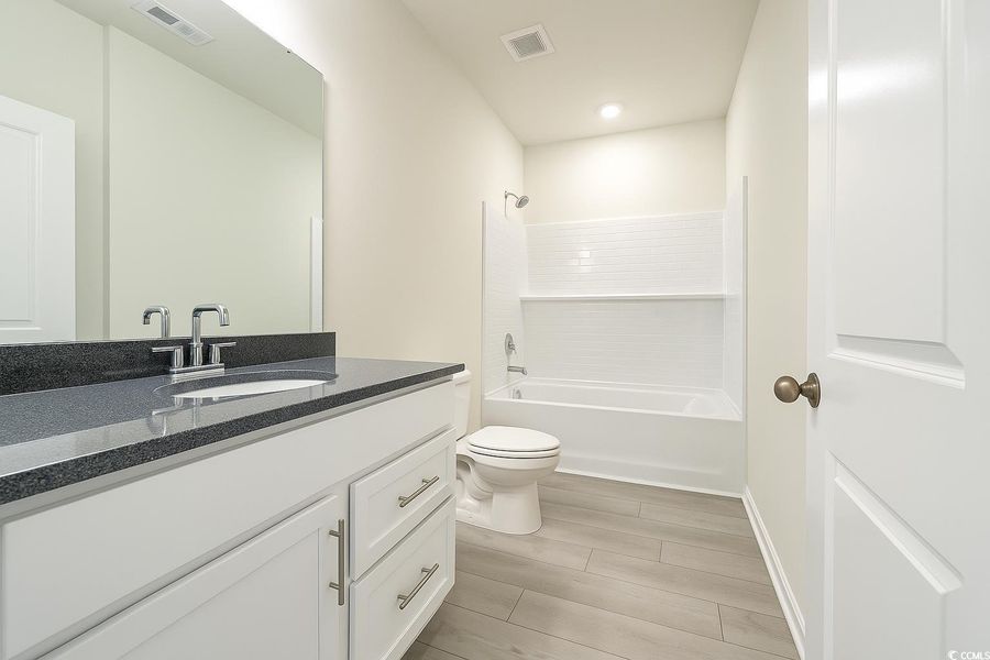 Bathroom featuring vanity, wood finish floors, and bathtub / shower combination Bathroom featuring vanity, wood finish floors, and bathtub / shower combination
