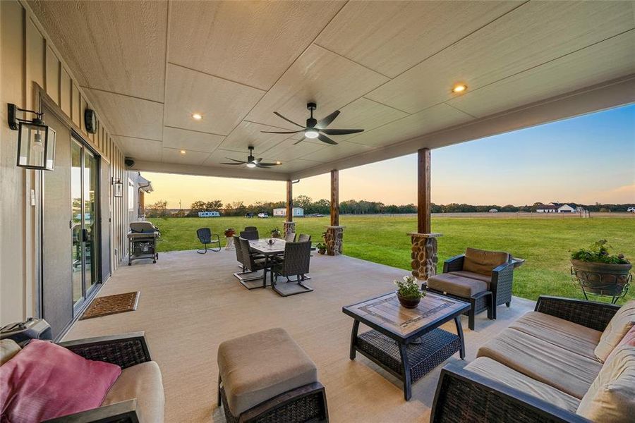 Patio terrace at dusk with outdoor dining space, a patio area, a yard, and a ceiling fan