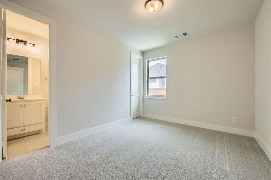 Unfurnished bedroom featuring light colored carpet and connected bathroom Unfurnished bedroom featuring light colored carpet and connected bathroom