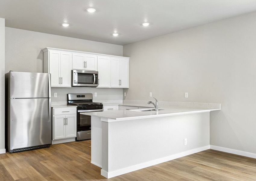 The kitchen has stainless steel appliances and plank flooring.