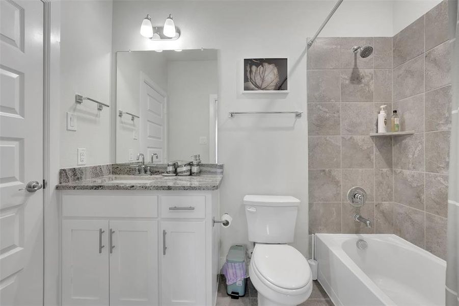 Full bathroom featuring tile patterned floors, vanity, toilet, and tiled shower / bath