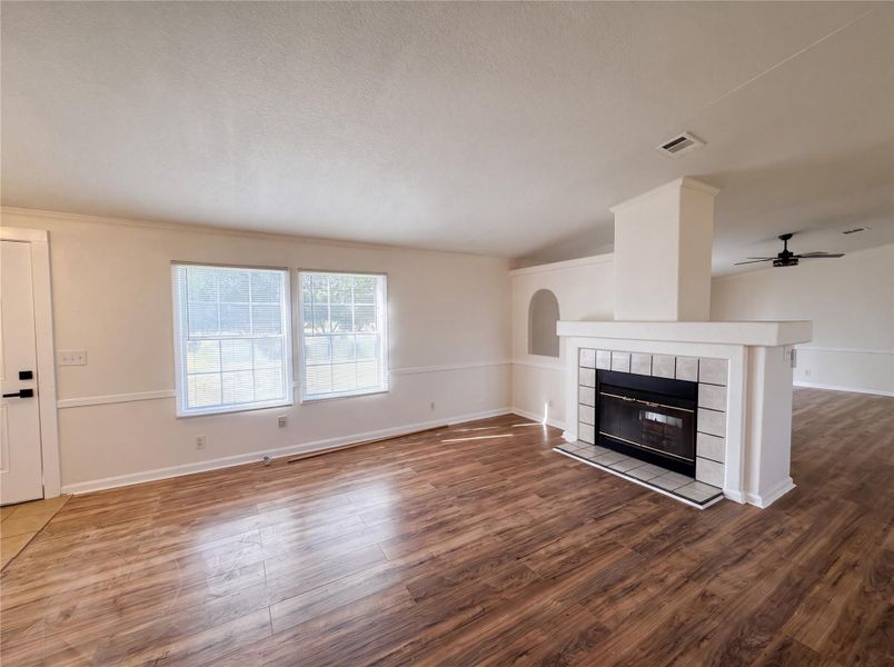 Rich wood-look flooring and a tiled fireplace anchor this inviting living space.