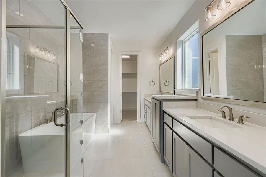 Bathroom featuring a stall shower, two vanities, a freestanding bath, and light tile patterned floors Bathroom featuring a stall shower, two vanities, a freestanding bath, and light tile patterned floors