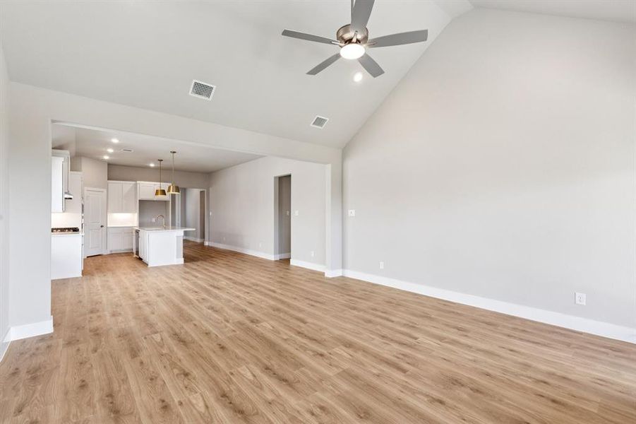 Unfurnished living room with high vaulted ceiling, light wood finished floors, recessed lighting, and ceiling fan