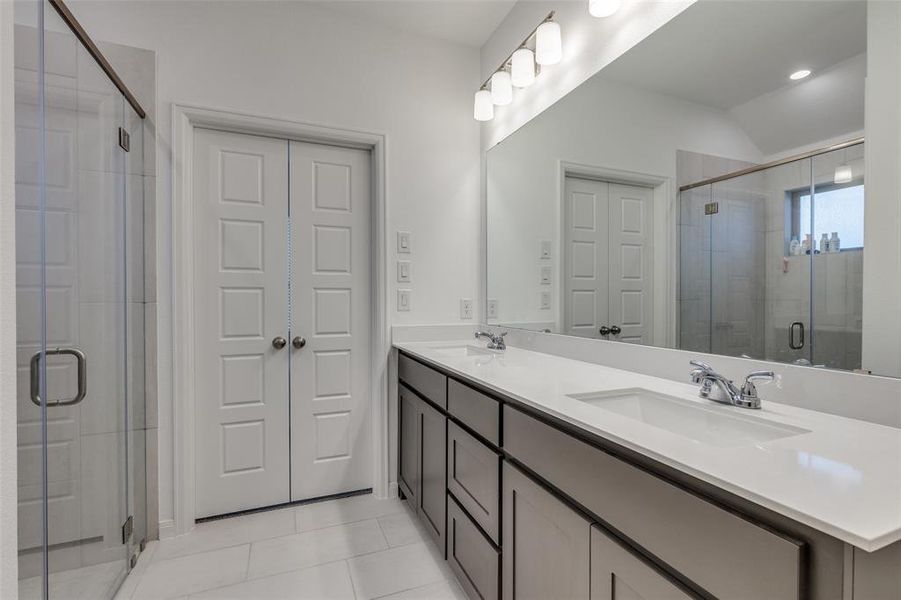 Bathroom with double vanity, a stall shower, and light tile patterned flooring