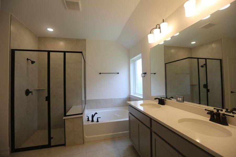 Modern bathroom featuring a double vanity with stone countertops, an expansive mirror, and a contemporary light fixture
