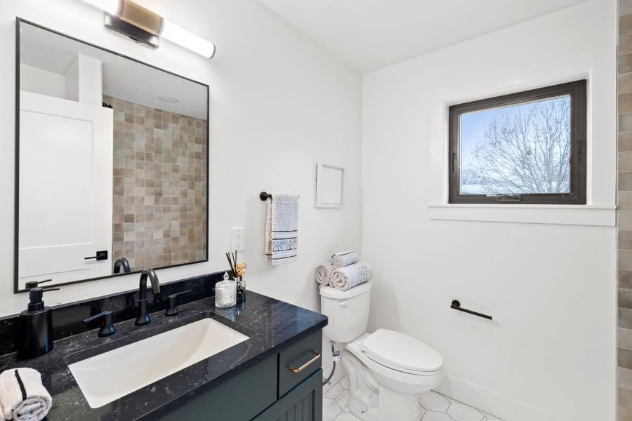 Bathroom with vanity, toilet, baseboards, and tile patterned flooring