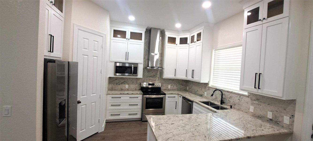 Kitchen with stainless steel appliances, light stone counters, tasteful backsplash, white cabinetry, and recessed lighting