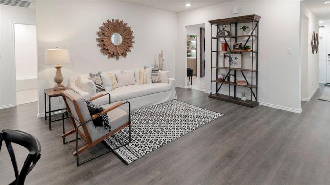 Spacious living area featuring plank wood-finish flooring, white walls, and a recessed lighting fixture Spacious living area featuring plank wood-finish flooring, white walls, and a recessed lighting fixture