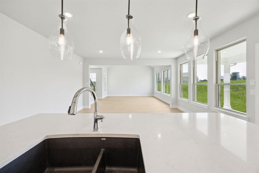 Kitchen with light wood-style floors, light stone countertops, pendant lighting, open floor plan, and recessed lighting