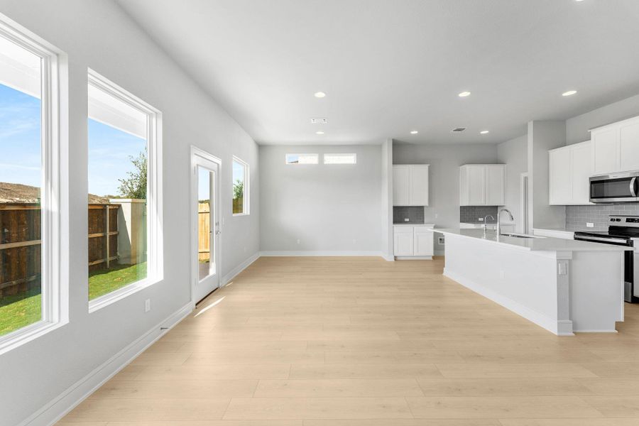 An open concept living area seamlessly connects to a modern kitchen, bathed in natural light from tall windows. An open concept living area seamlessly connects to a modern kitchen, bathed in natural light from tall windows.
