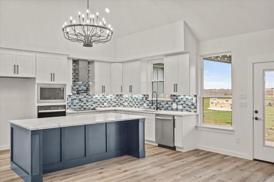 Kitchen featuring built in microwave, white cabinetry, electric stovetop, wall oven, and wall chimney exhaust hood