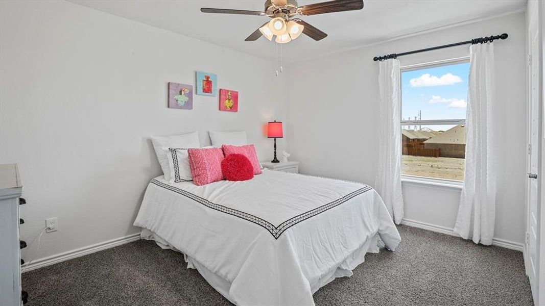 Bedroom featuring a ceiling fan and dark carpet