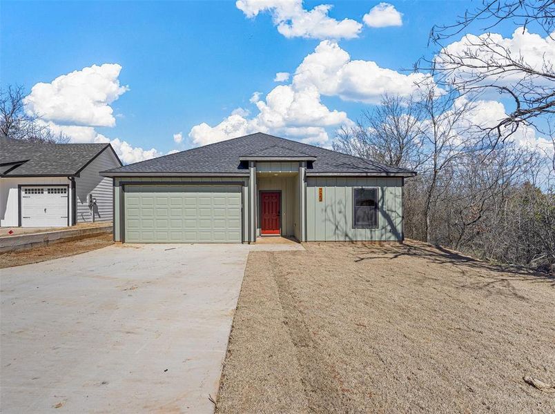 View of front of home featuring an attached garage, concrete driveway, roof with shingles, and board and batten siding