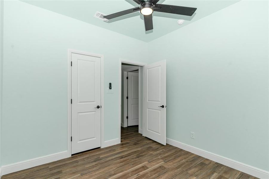 Unfurnished bedroom featuring dark wood-style floors and ceiling fan