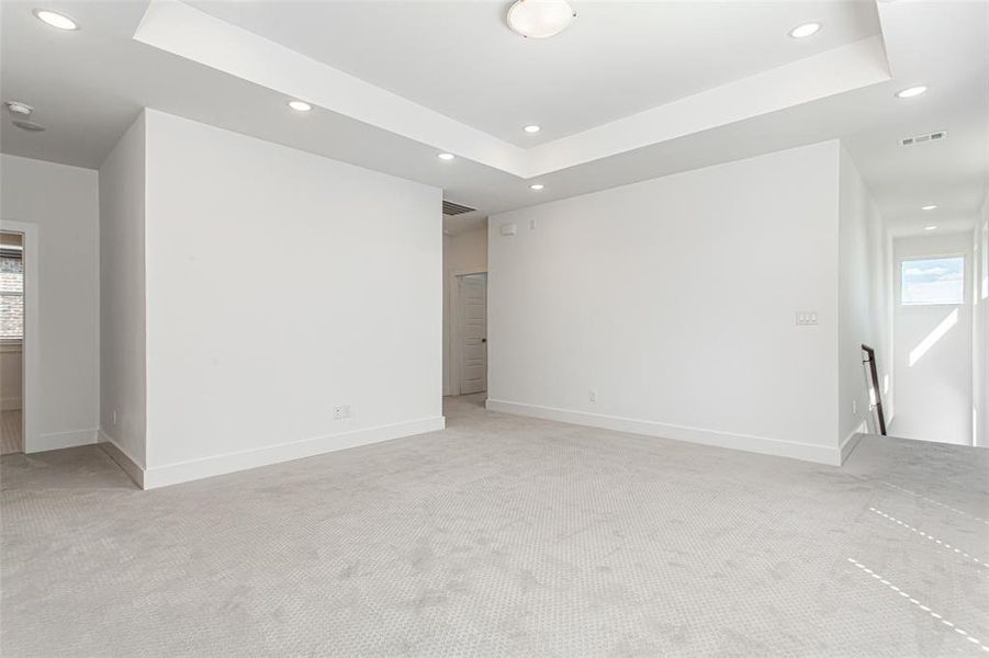 Empty room featuring healthy amount of natural light, recessed lighting, a tray ceiling, and light carpet