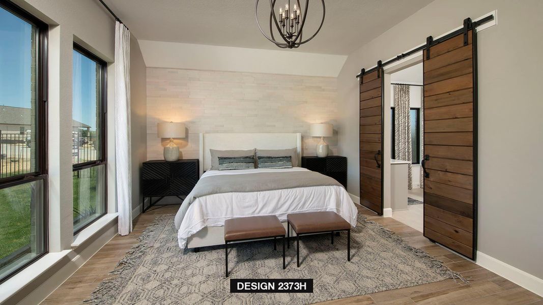 Bedroom featuring a barn door, light wood-type flooring, a chandelier, and connected bathroom Bedroom featuring a barn door, light wood-type flooring, a chandelier, and connected bathroom