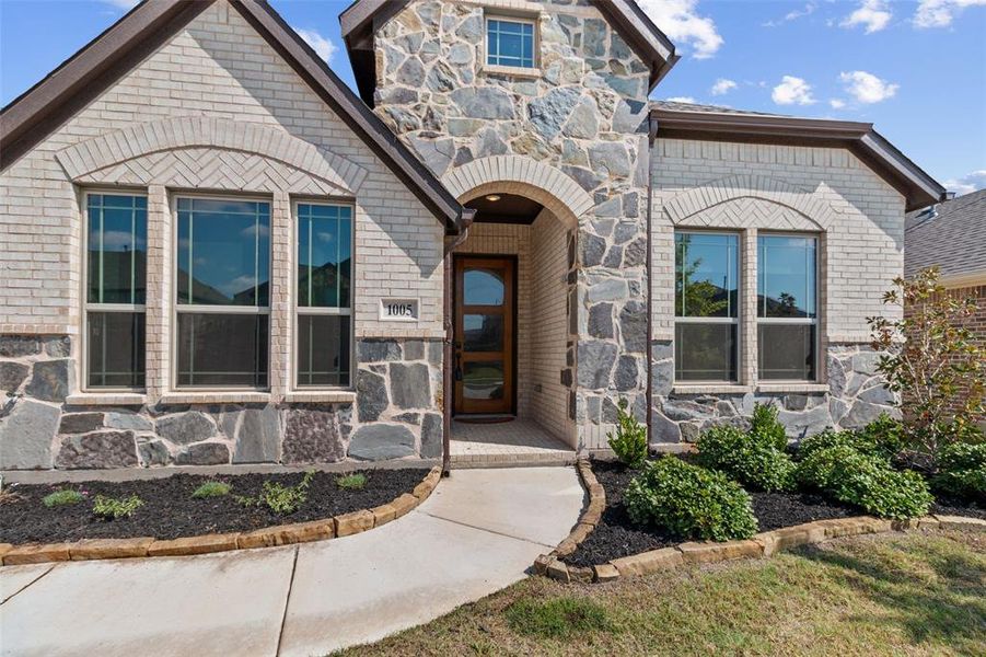 Entrance to property featuring stone siding and brick siding