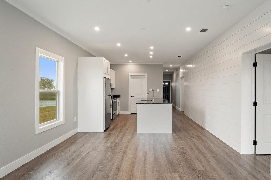 Kitchen featuring white cabinets, light wood-style flooring, freestanding refrigerator, recessed lighting, and open floor plan