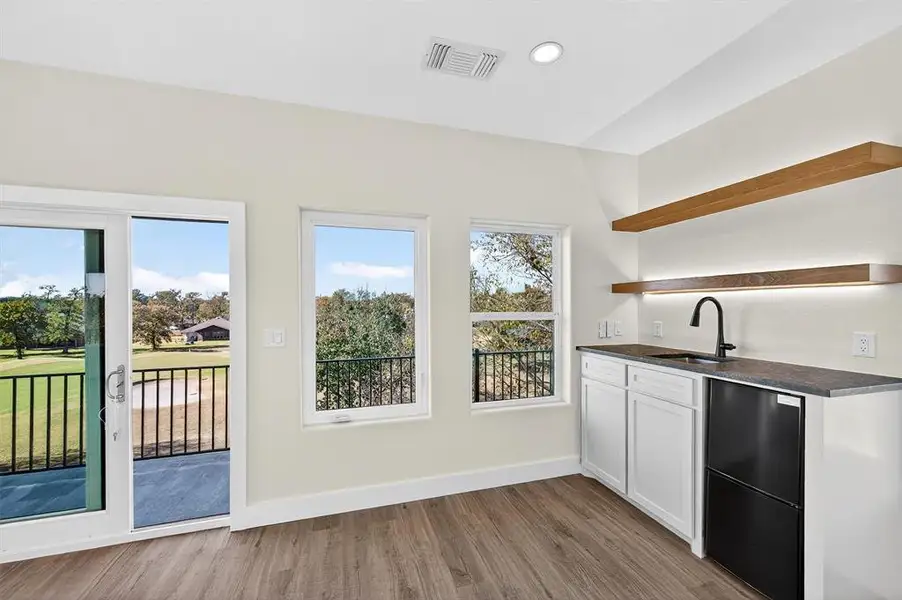 Kitchen featuring open shelves, white cabinets, light wood-style flooring, dark stone countertops, and dishwasher