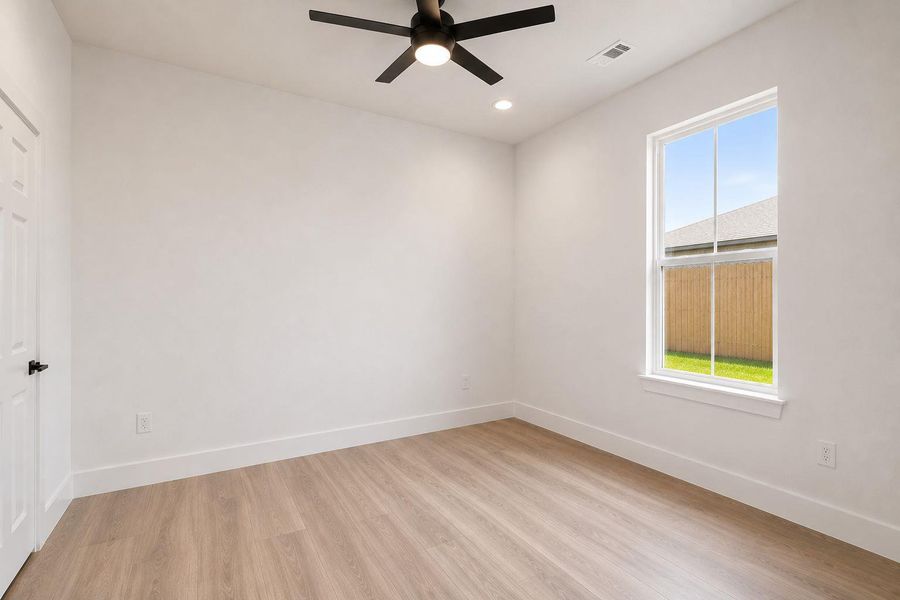 2nd bedroom/ensuite/inlaw. A well-lit room featuring contemporary wood flooring and a refreshing ceiling fan.