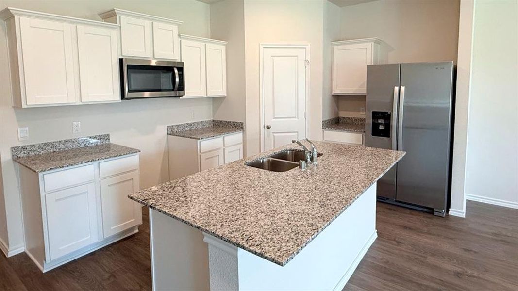 Kitchen featuring appliances with stainless steel finishes, white cabinets, light stone countertops, and dark wood-type flooring Kitchen featuring appliances with stainless steel finishes, white cabinets, light stone countertops, and dark wood-type flooring