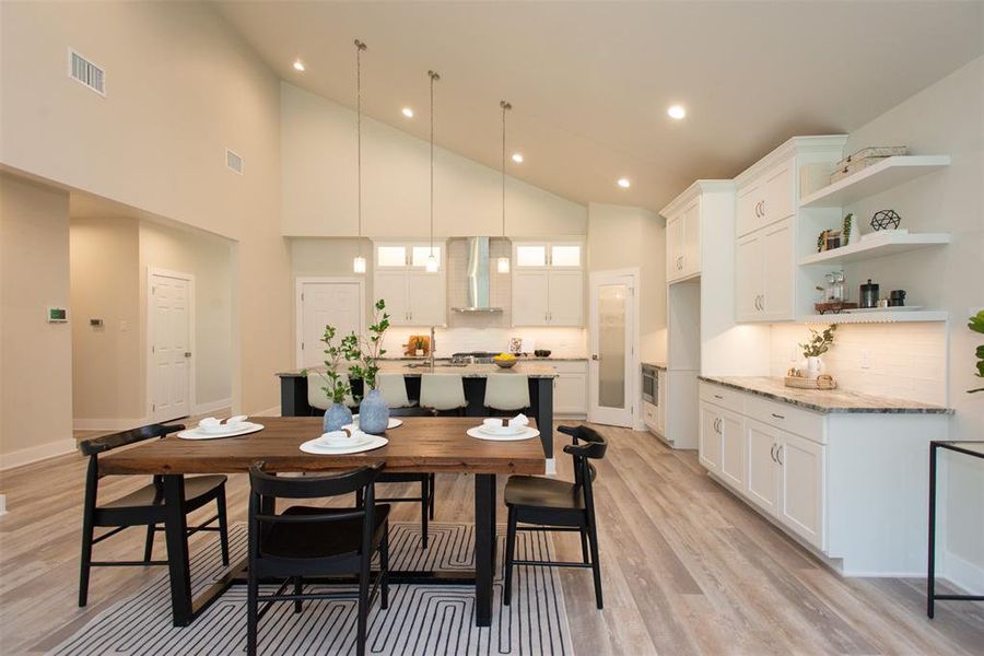 Dining space featuring light hardwood / wood-style flooring and high vaulted ceiling