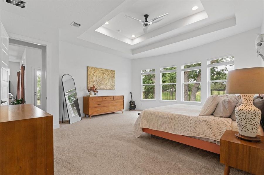 Here, a tray ceiling, wall of windows, and spa-like ensuite bath await