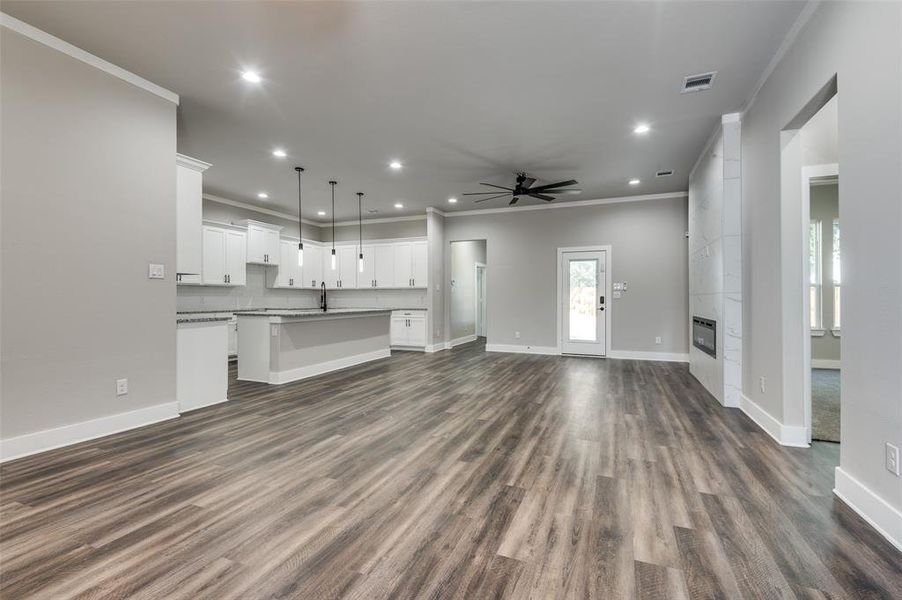 Unfurnished living room with crown molding, a ceiling fan, recessed lighting, dark wood finished floors, and a tiled fireplace Unfurnished living room with crown molding, a ceiling fan, recessed lighting, dark wood finished floors, and a tiled fireplace