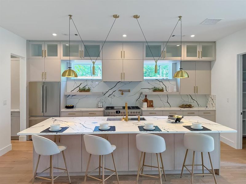 Kitchen featuring light wood-type flooring, glass insert cabinets, a kitchen bar, and recessed lighting Kitchen featuring light wood-type flooring, glass insert cabinets, a kitchen bar, and recessed lighting