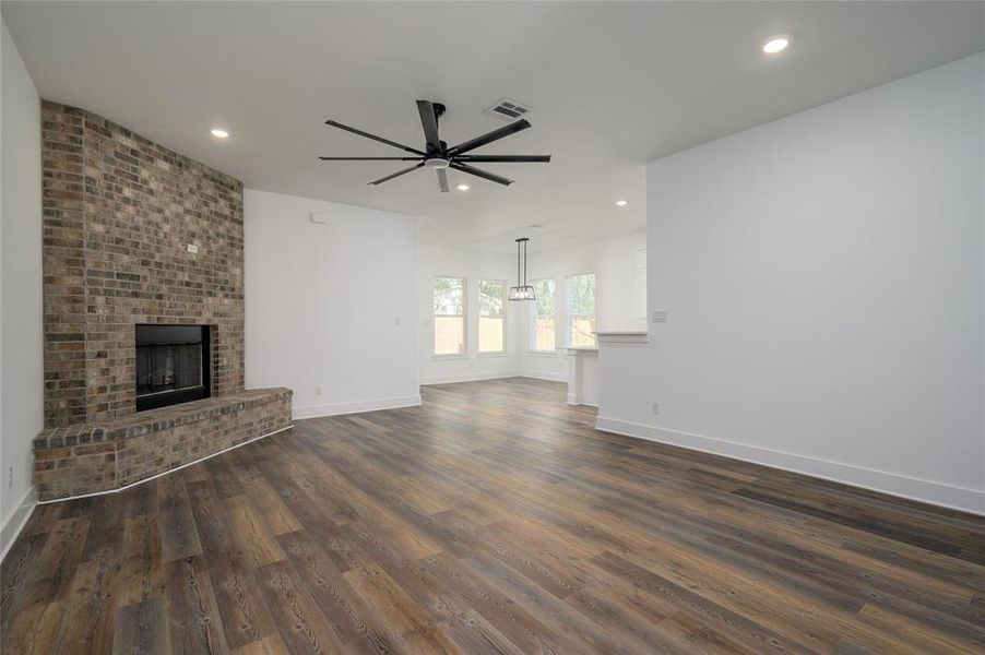 Unfurnished living room featuring a fireplace, dark wood-type flooring, and ceiling fan