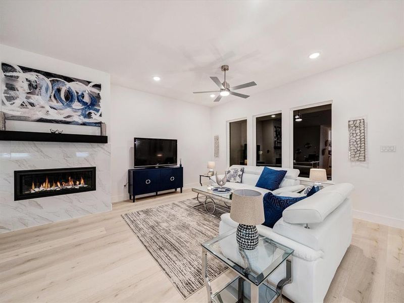 Living area with a high end fireplace, light wood-type flooring, recessed lighting, and a ceiling fan Living area with a high end fireplace, light wood-type flooring, recessed lighting, and a ceiling fan