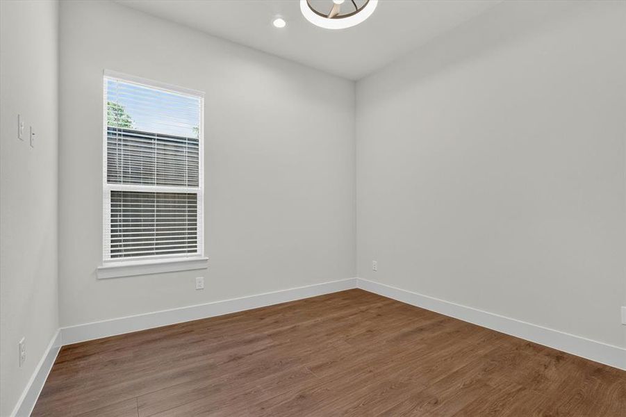Room featuring wood-finish flooring, a single window with white blinds, and a contemporary ceiling light fixture
