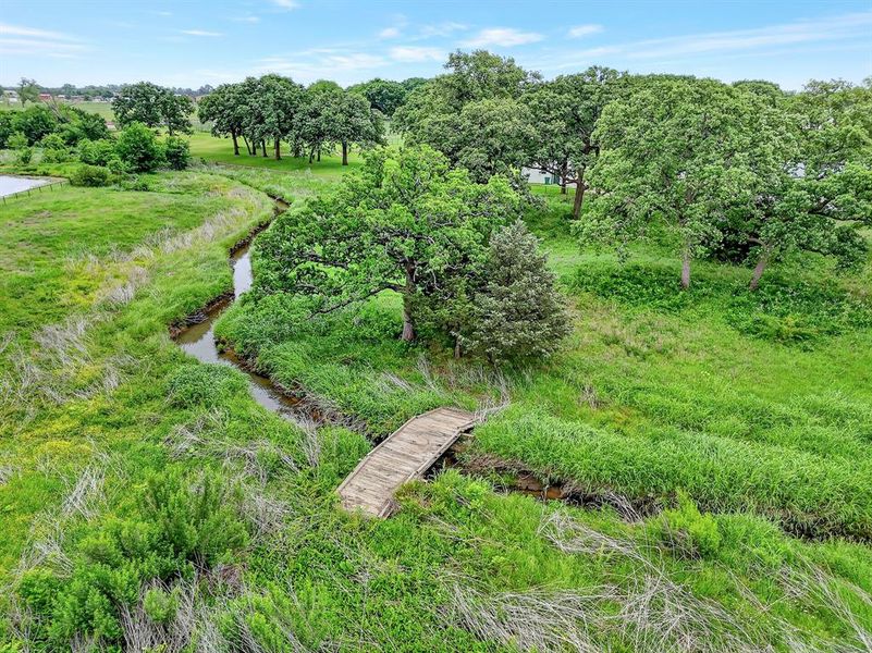 Creek with bridge located behind the fenced area of the property.