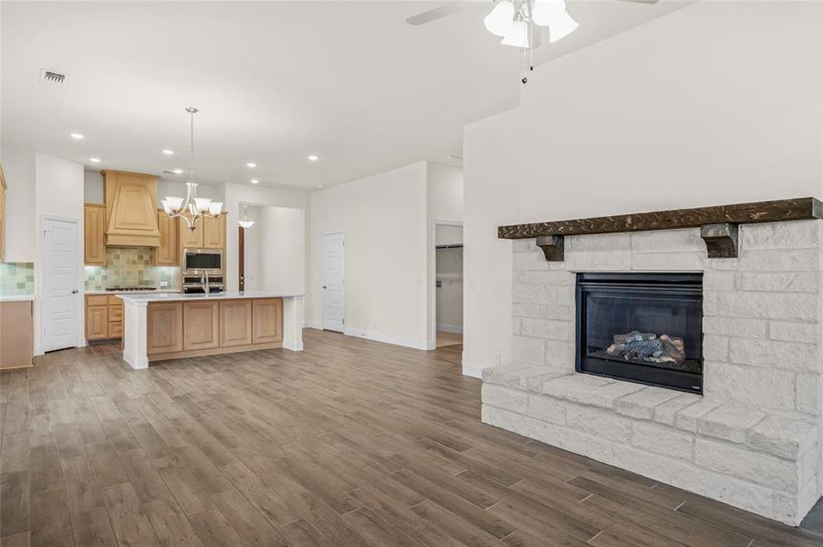 Kitchen featuring open floor plan, tasteful backsplash, a chandelier, a stone fireplace, and recessed lighting Kitchen featuring open floor plan, tasteful backsplash, a chandelier, a stone fireplace, and recessed lighting