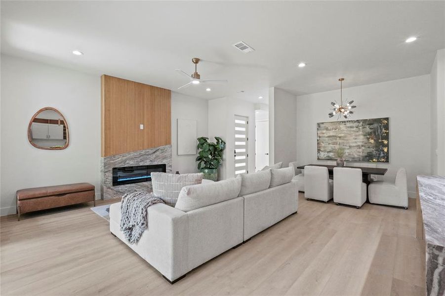 Living room featuring ceiling fan with notable chandelier, light hardwood / wood-style floors, and a premium fireplace