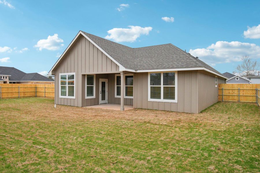 Rear view of house with a fenced backyard, board and batten siding, a yard, and roof with shingles