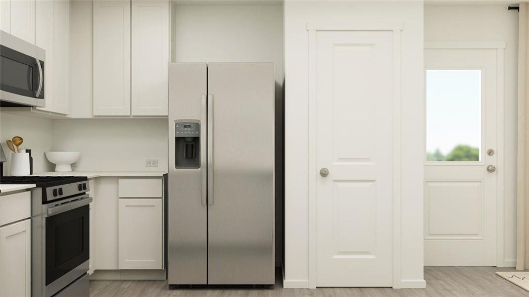 Kitchen featuring white cabinets, stainless steel appliances, and light hardwood / wood-style flooring