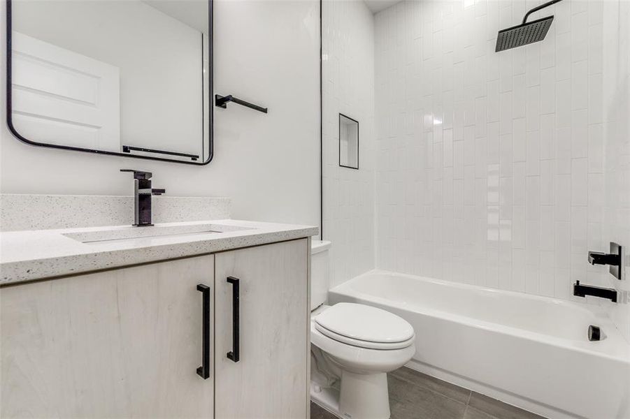 Full bathroom downstairs with tile patterned flooring, toilet, shower / bath combination, and vanity