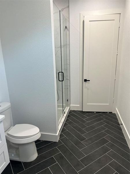 Bathroom featuring tile patterned flooring, vanity, toilet, and an enclosed shower