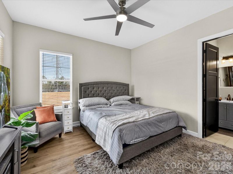 Bright and inviting bedroom featuring neutral tones, a ceiling fan/light and convenient access to a private ensuite bathroom.