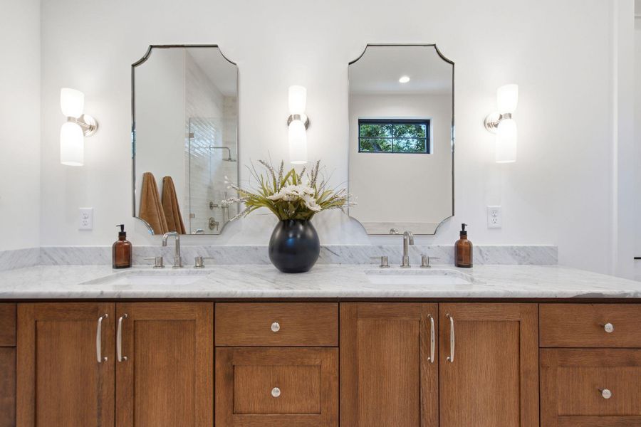 Custom wood cabinetry anchors a refined vanity topped with elegant natural stone.