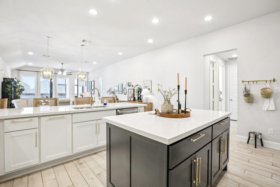 Dual tone kitchen featuring decorative light fixtures, a spacious island, light stone counters, dual tone cabinetry, and light wood-type flooring