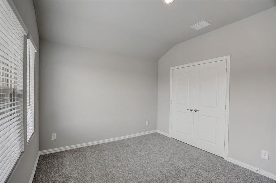 Unfurnished bedroom with a closet, lofted ceiling, and carpet flooring