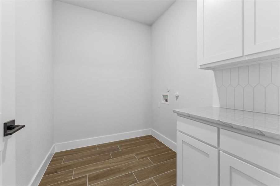Laundry area featuring wood finish floors, hookup for a washing machine, and cabinet space