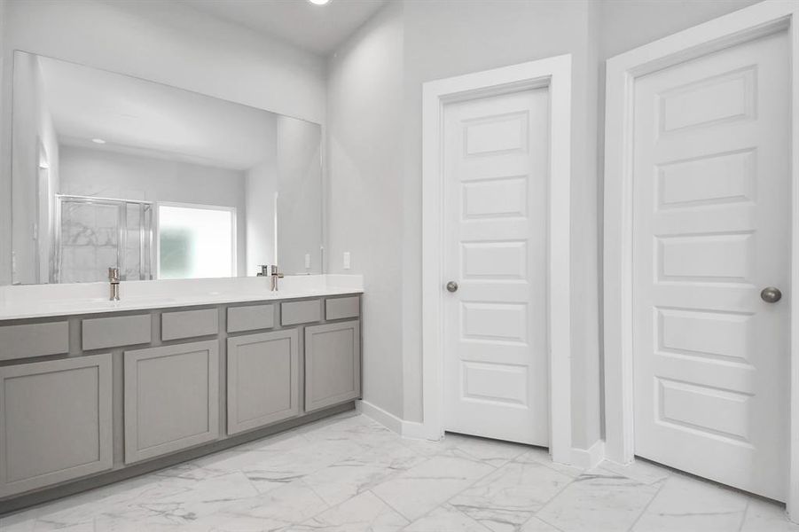 Escape to a spa-like oasis in this primary bathroom. Features elegant vanity with light countertops, modern hardware, and bright recessed lights.