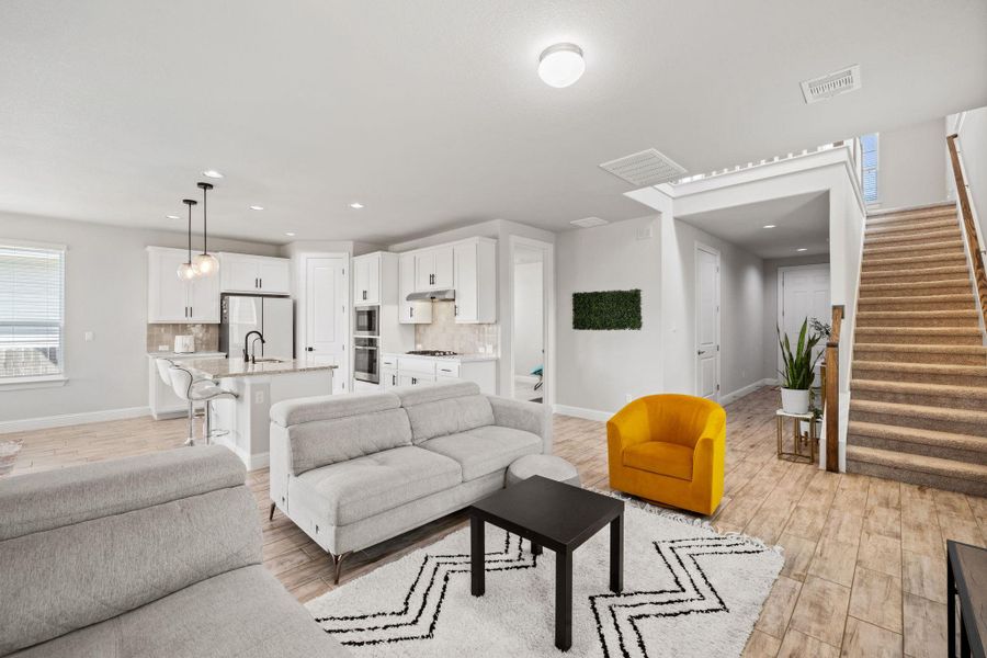 Living room featuring stairway, recessed lighting, and light wood-style floors Living room featuring stairway, recessed lighting, and light wood-style floors
