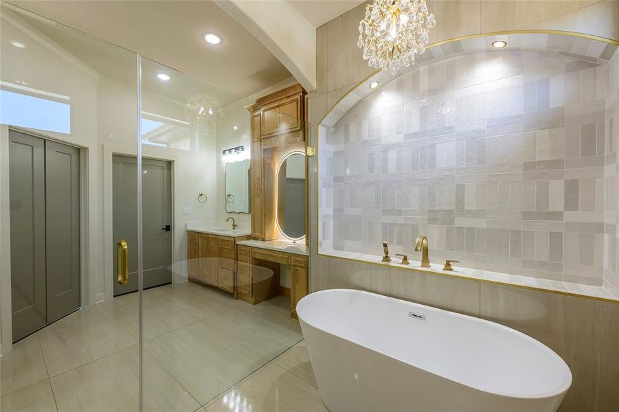 Full bath featuring double vanity, light tile patterned floors, suspended lighting, and a freestanding tub