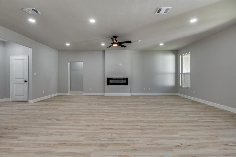 Unfurnished living room with light wood-style floors, a glass covered fireplace, recessed lighting, and a ceiling fan Unfurnished living room with light wood-style floors, a glass covered fireplace, recessed lighting, and a ceiling fan