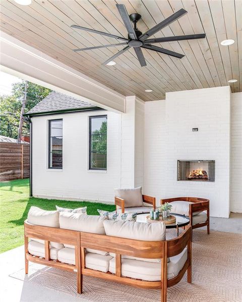 View of patio featuring ceiling fan and an outdoor living space with a fireplace